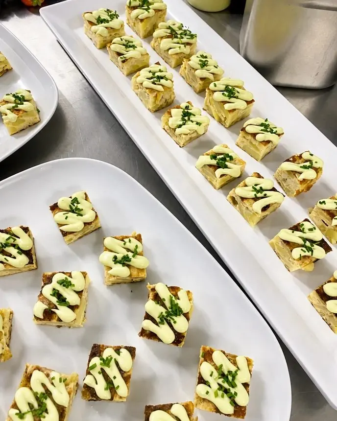 Potato tortilla canapés with aioli and chives on platters at a Crosta catering