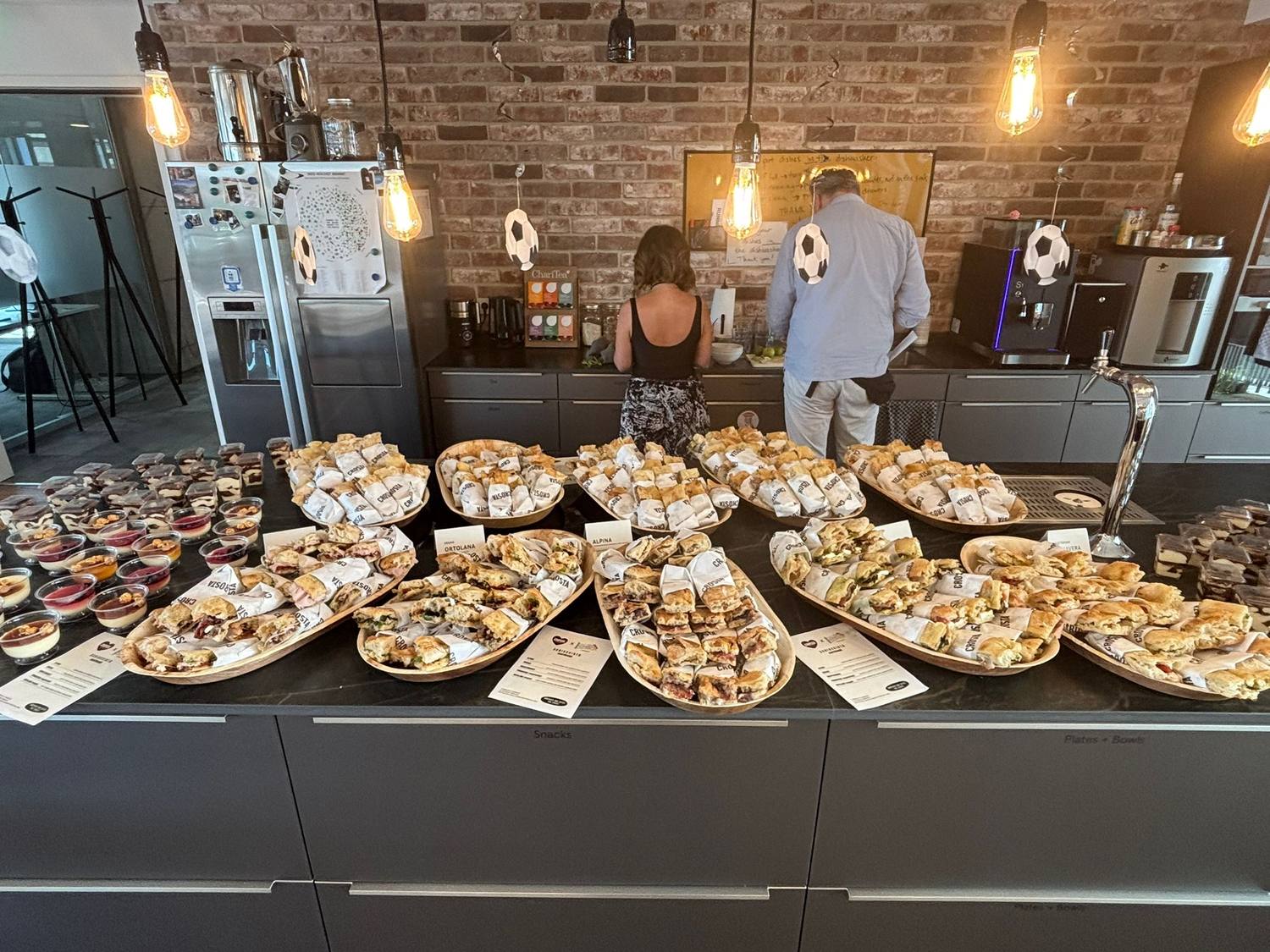 A Crosta catering buffet laid out on an office counter, boards of schiacciata and dessert cups