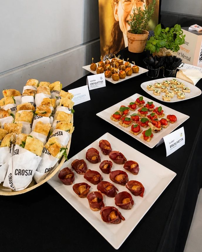 Basket of wrapped Crosta schiacciata bites beside antipasti platters at a catering buffet in Berlin
